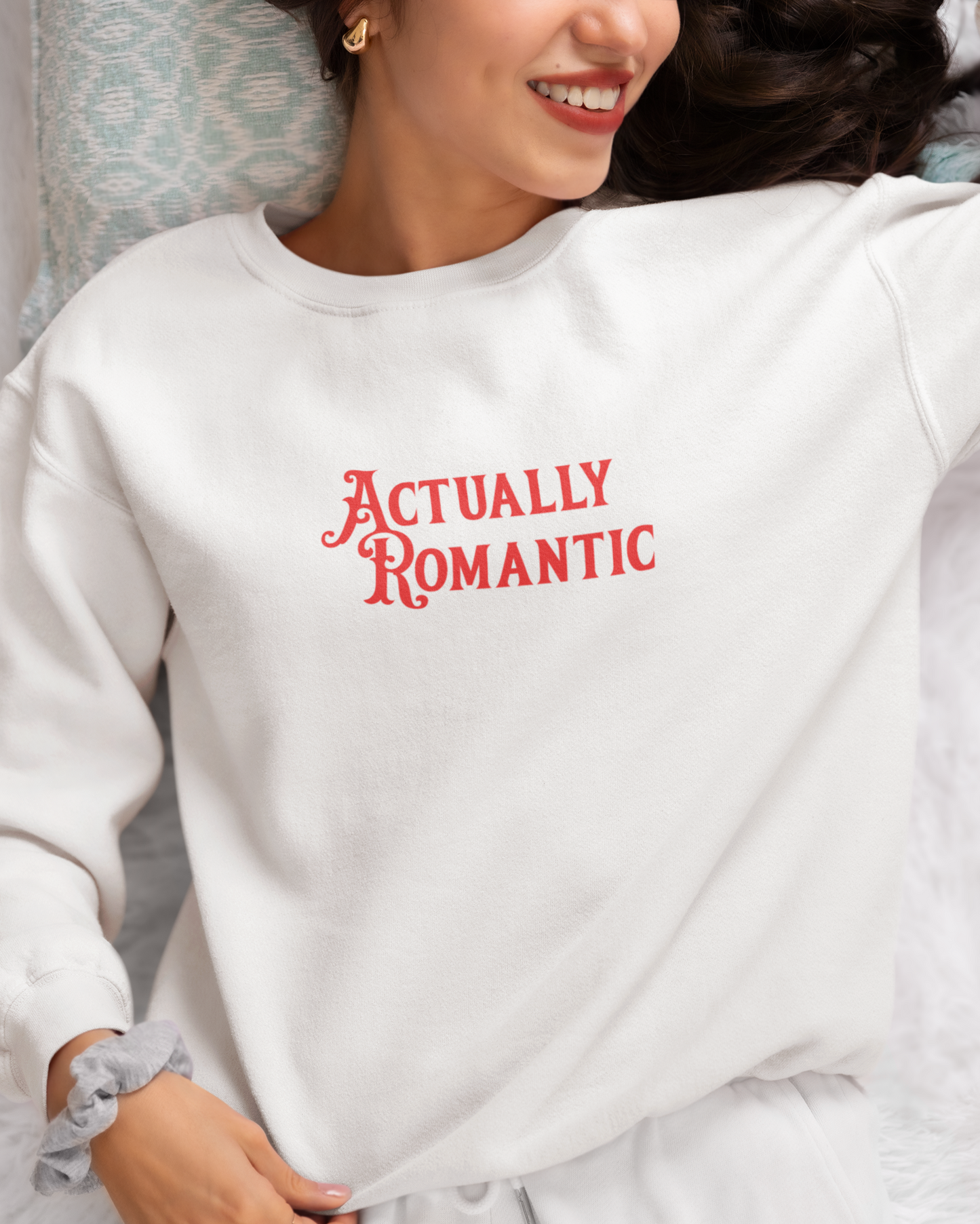 Person wearing a white sweatshirt with 'Actually Romantic' text in red.